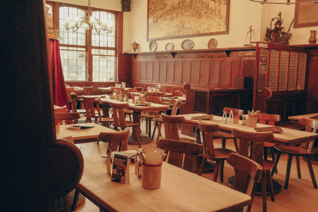 Brauhaus Köln - Brauerei zur Malzmühle. Ein Bild. Zu erkennen ist der der Gastraum vom kölsches Brauhaus in der Innenstadt von Köln am Heumarkt. Die Tische und Stühle sind zu erkennen. Auf den Tischen ist schon Besteck und die Speisekarte vorbereitet.