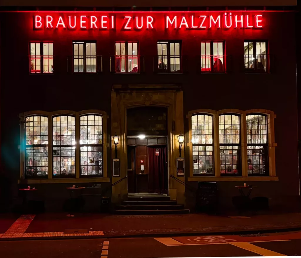 Außenansicht mit Außenbeleuchtung der Front der Brauerei zur Malzmühle - Brauhaus Köln - in der Nacht.